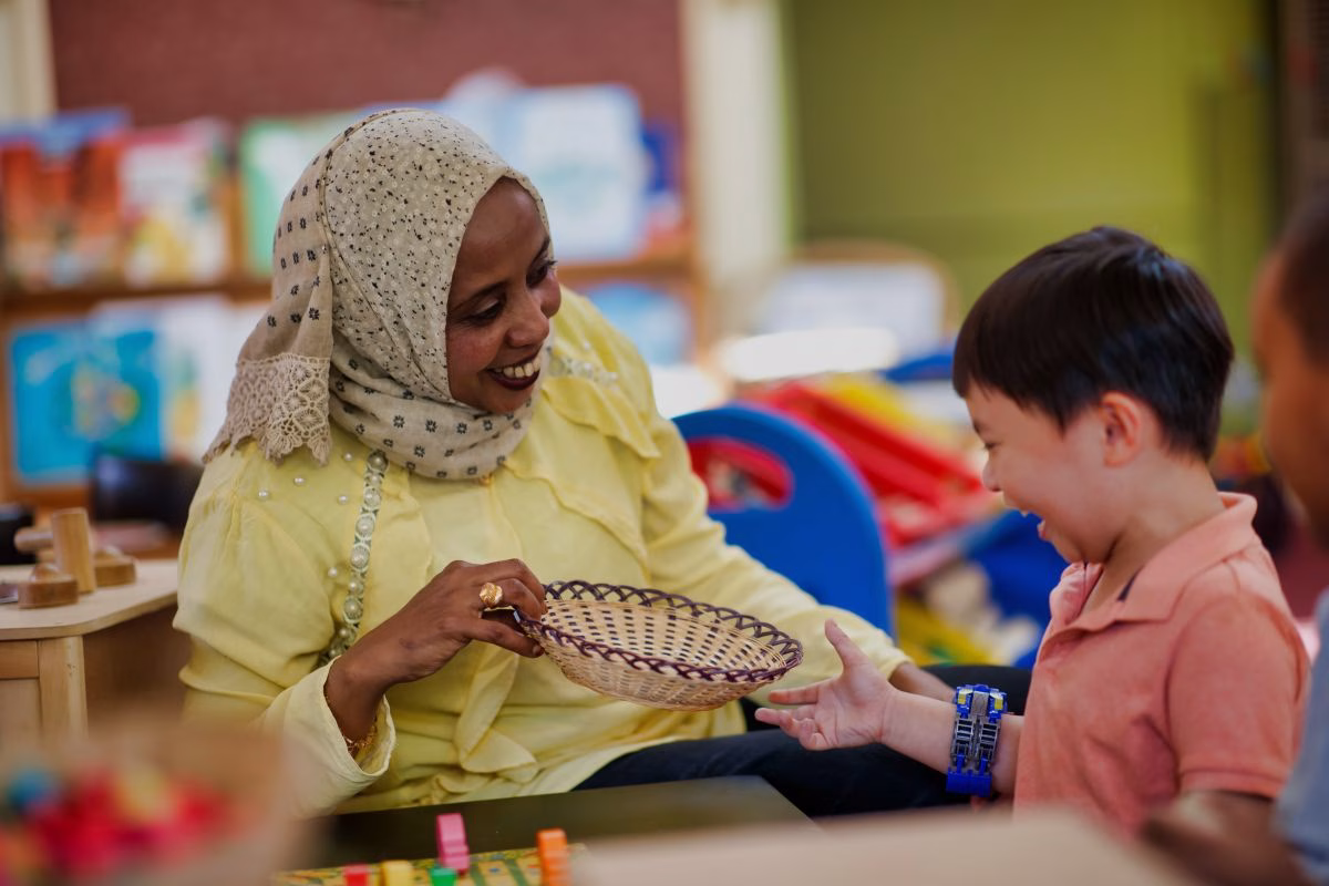 carer-holding-woven-basket-laughing-with-child.avif