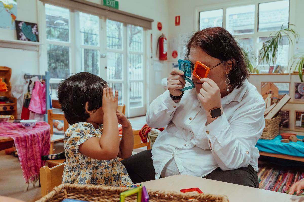 child-and-educator-with-transparent-colourful-tiles-over-their-eyes.avif