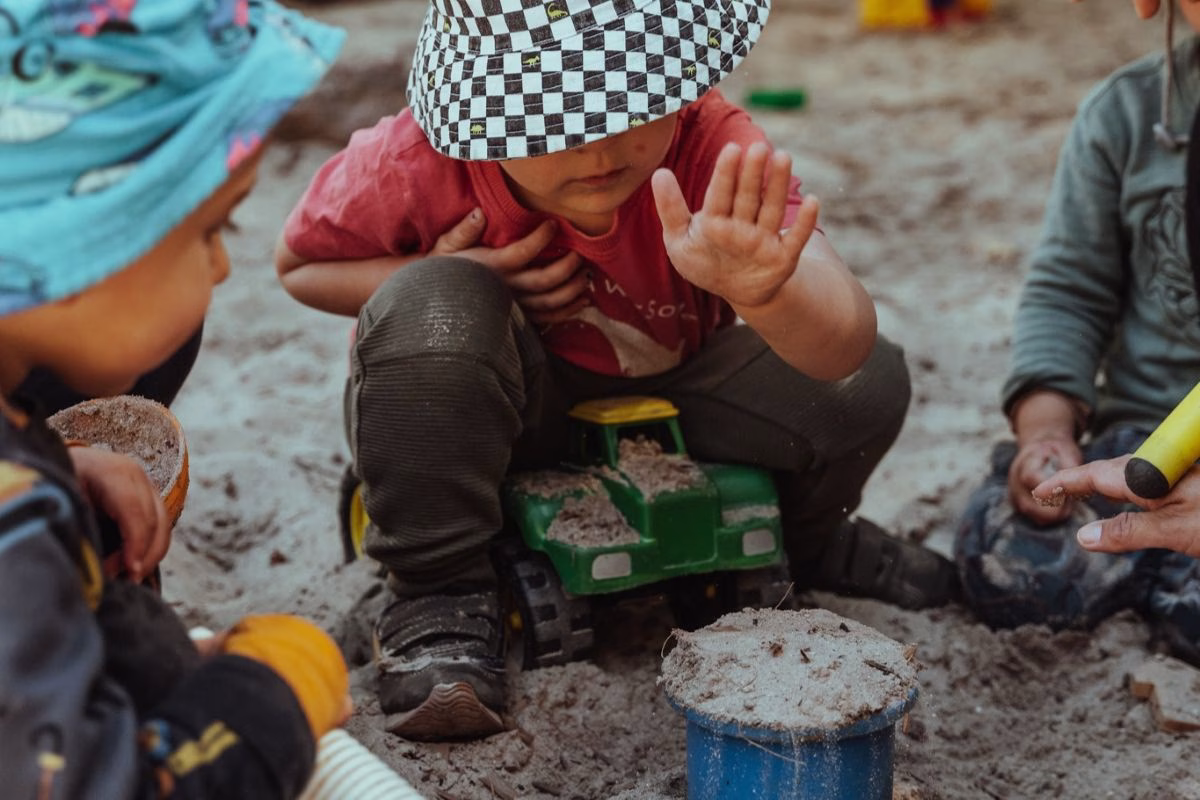children-in-hats-playing-in-sandpit.avif