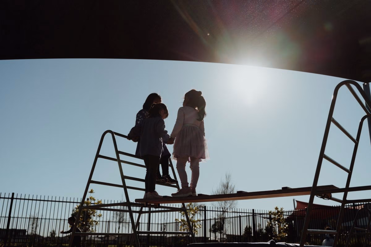 three-children-outside-on-climbing-equipment.avif