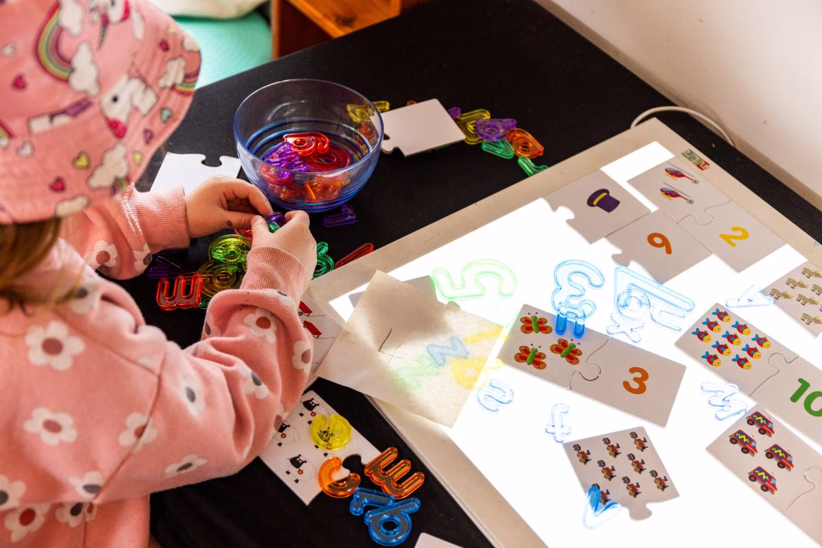 child-experimenting-with-number-jigsaws-over-a-lightbox.avif
