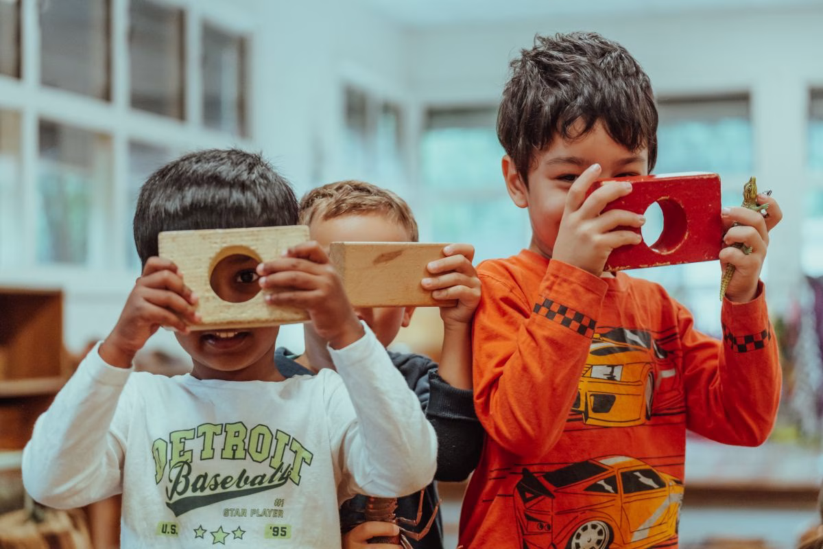 children-hold-wooden-blocks-up-to-their-faces.avif